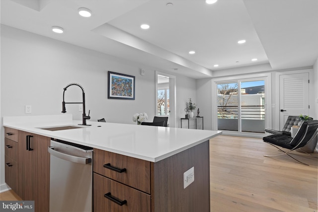 kitchen featuring light wood finished floors, dishwasher, a tray ceiling, recessed lighting, and a sink