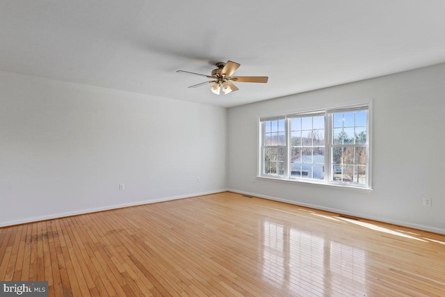 empty room with a ceiling fan, baseboards, and hardwood / wood-style flooring