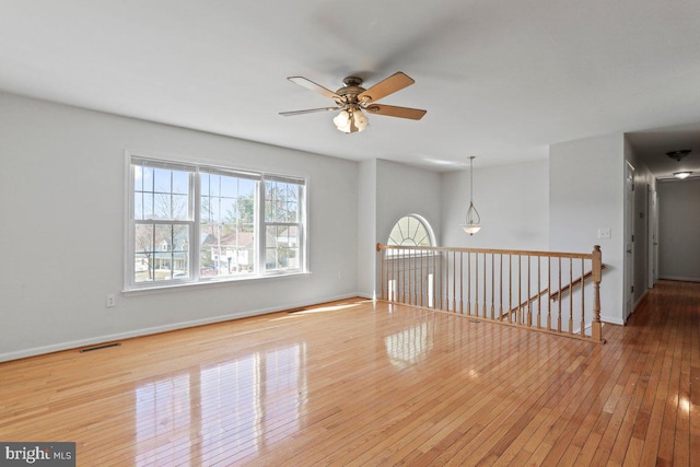 spare room featuring visible vents, baseboards, ceiling fan, and hardwood / wood-style flooring