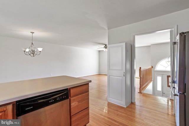 kitchen featuring pendant lighting, ceiling fan with notable chandelier, brown cabinets, appliances with stainless steel finishes, and light wood-style floors