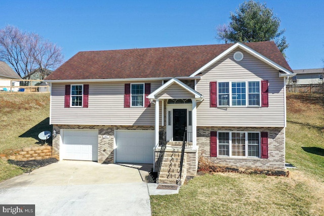 raised ranch with brick siding, fence, concrete driveway, a front yard, and an attached garage