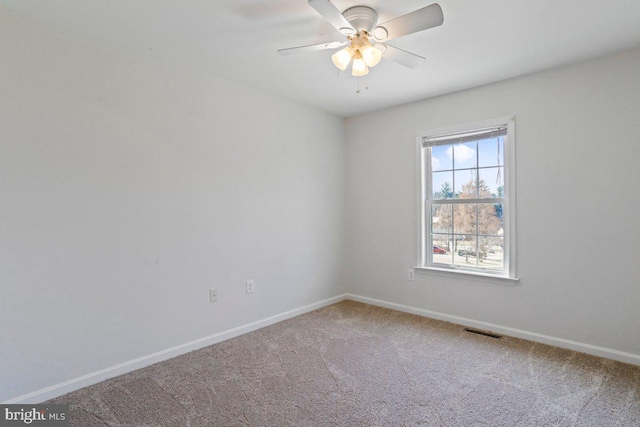 empty room with baseboards, visible vents, carpet floors, and ceiling fan