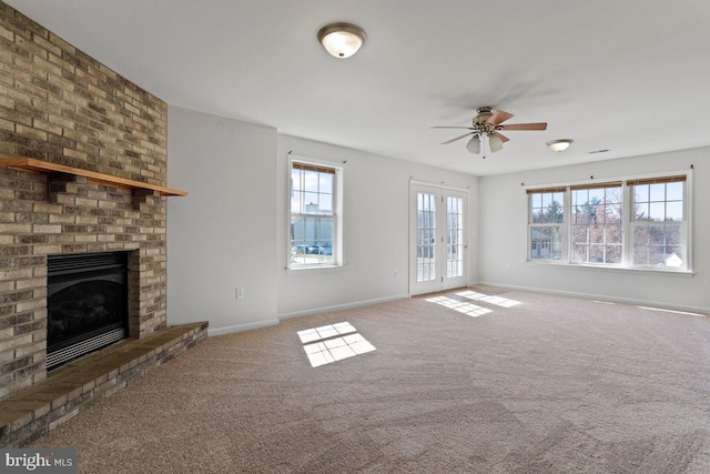 unfurnished living room featuring baseboards, ceiling fan, french doors, a brick fireplace, and carpet flooring