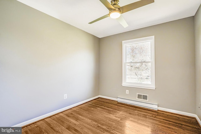 unfurnished room with visible vents, wood finished floors, baseboards, baseboard heating, and ceiling fan