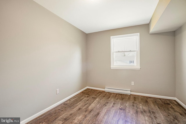 spare room featuring baseboard heating, baseboards, and wood finished floors