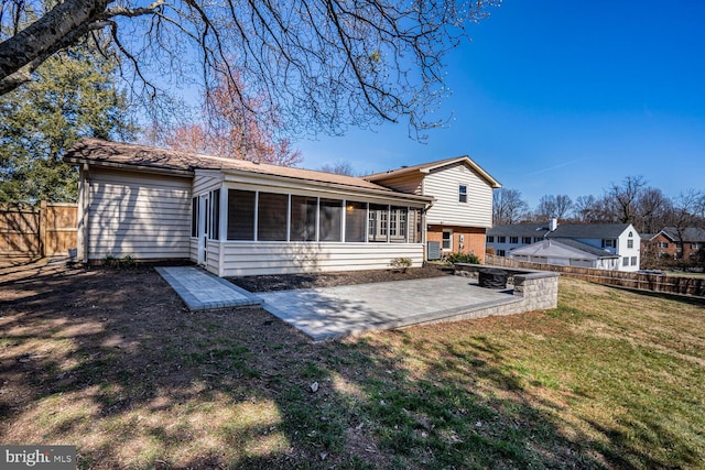 rear view of house with a lawn, fence, a sunroom, brick siding, and a patio area