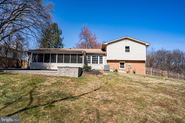 back of property with brick siding, a lawn, fence, and a sunroom