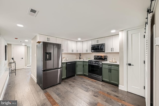 kitchen with visible vents, dark wood finished floors, a barn door, stainless steel appliances, and green cabinetry