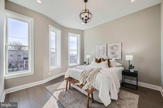 bedroom with an inviting chandelier, baseboards, and dark wood-style flooring