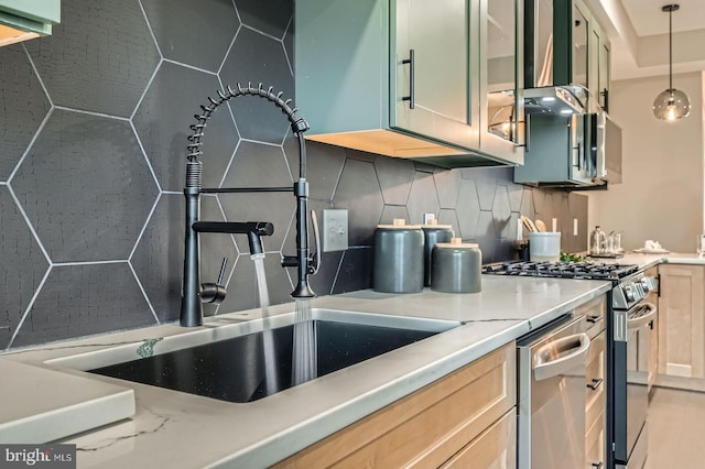 kitchen with glass insert cabinets, decorative light fixtures, gas range, decorative backsplash, and a sink