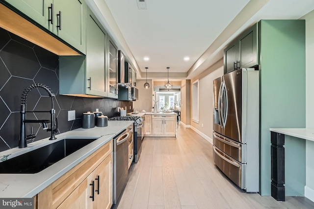 kitchen featuring a sink, stainless steel appliances, green cabinetry, and a peninsula