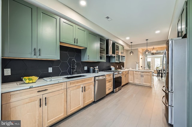 kitchen featuring visible vents, a sink, appliances with stainless steel finishes, a peninsula, and green cabinetry