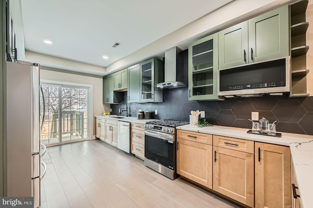 kitchen with tasteful backsplash, green cabinetry, stainless steel appliances, wall chimney exhaust hood, and open shelves