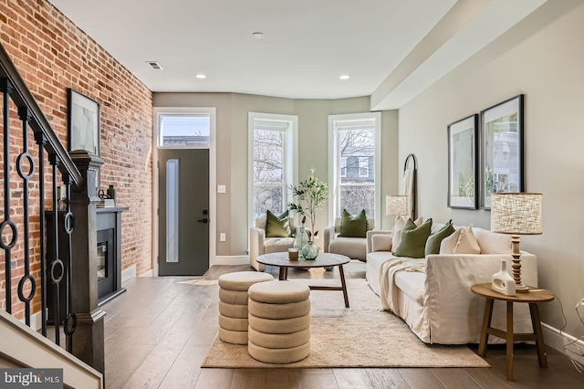 living area with plenty of natural light, a fireplace, baseboards, and wood-type flooring