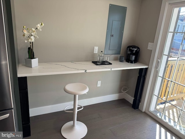 interior space with electric panel, baseboards, and wood finished floors