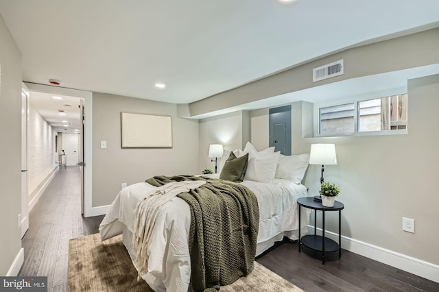 bedroom with electric panel, visible vents, baseboards, and dark wood finished floors