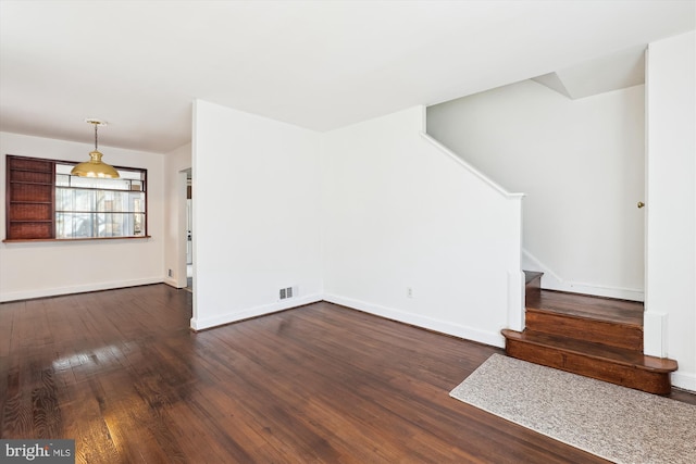 unfurnished living room featuring dark wood-style floors, visible vents, stairs, and baseboards