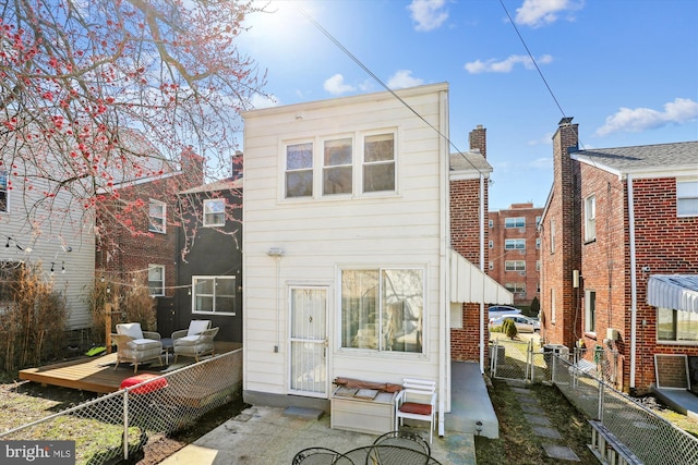 rear view of property featuring a gate, a deck, and fence