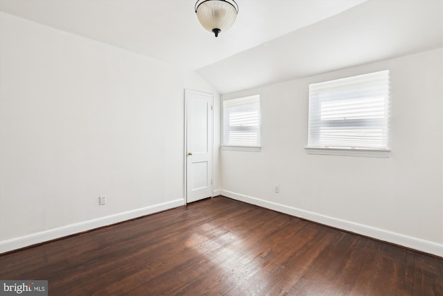 empty room with baseboards, dark wood-style flooring, and vaulted ceiling