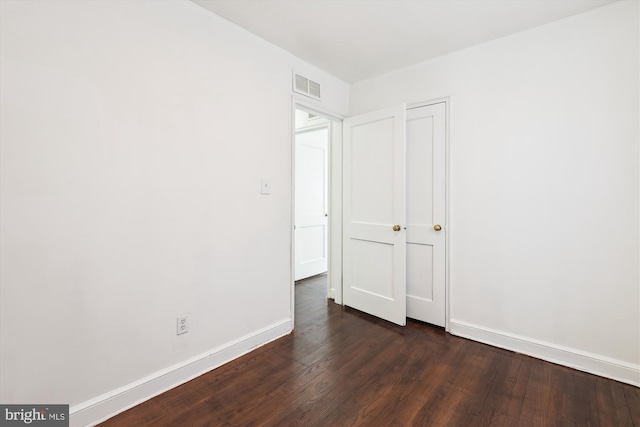 unfurnished bedroom featuring visible vents, baseboards, and dark wood-style flooring