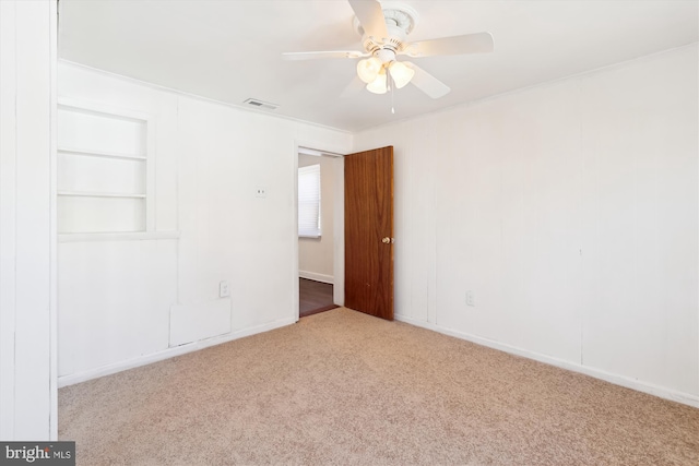 unfurnished bedroom with visible vents, carpet, ornamental molding, and a ceiling fan