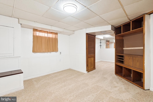 finished below grade area with a paneled ceiling and light colored carpet