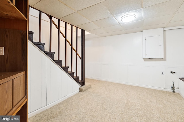 finished basement featuring carpet flooring, stairway, and a paneled ceiling