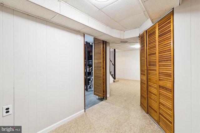 hallway featuring stairway, baseboards, a paneled ceiling, and carpet