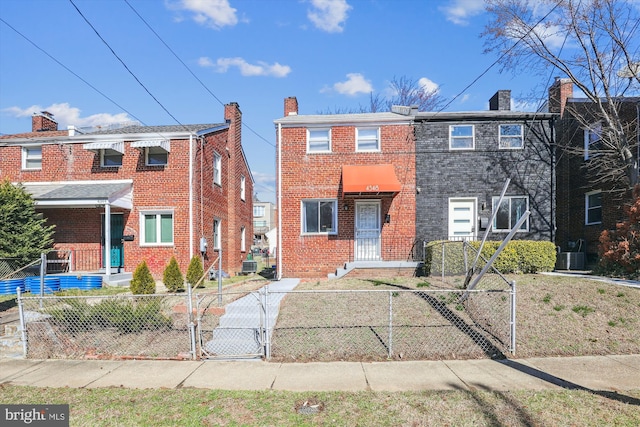 view of property featuring a gate, central AC unit, a chimney, a fenced front yard, and brick siding