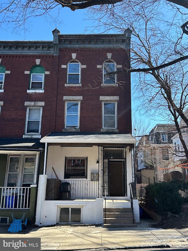 view of front facade with brick siding and covered porch