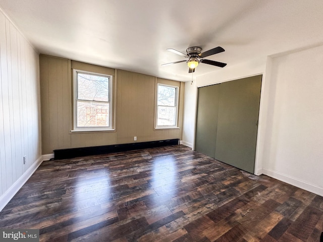 unfurnished bedroom with baseboards, dark wood-style floors, and a ceiling fan