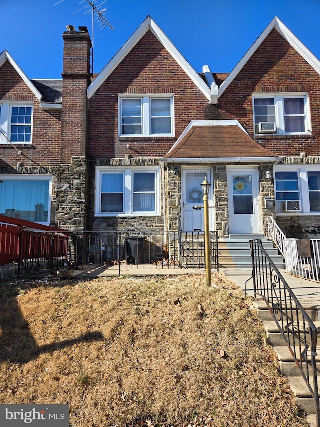 view of front of house with a fenced front yard, stone siding, brick siding, and a chimney