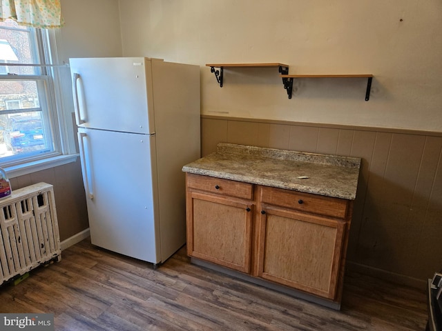 kitchen featuring open shelves, dark wood finished floors, radiator heating unit, freestanding refrigerator, and wainscoting