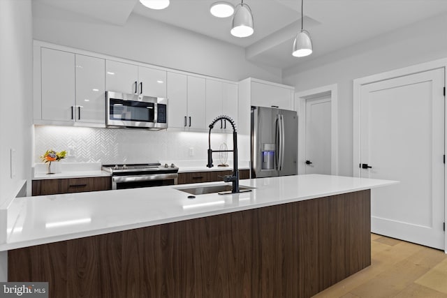 kitchen with a sink, white cabinets, stainless steel appliances, and modern cabinets