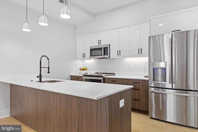 kitchen with light wood-style flooring, a sink, appliances with stainless steel finishes, white cabinets, and decorative backsplash