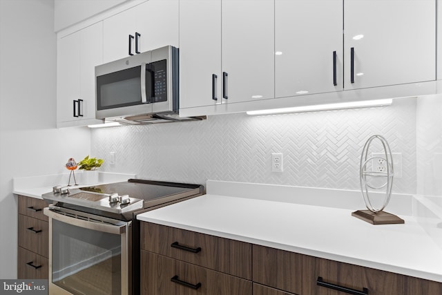 kitchen with stainless steel appliances, modern cabinets, white cabinets, and light countertops