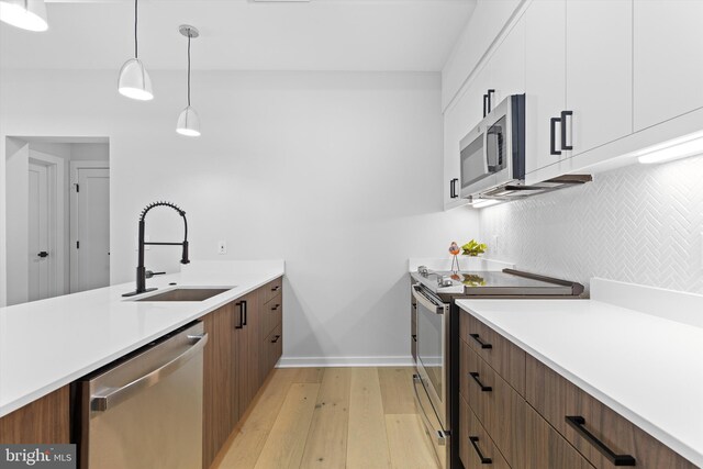 kitchen featuring white cabinetry, light countertops, appliances with stainless steel finishes, and a sink