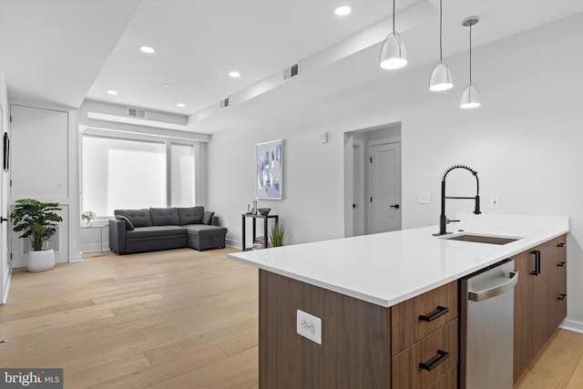 kitchen with light wood finished floors, open floor plan, light countertops, recessed lighting, and a sink