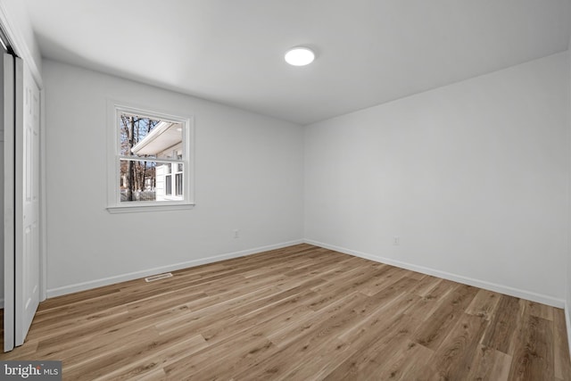 spare room featuring visible vents, baseboards, and light wood finished floors