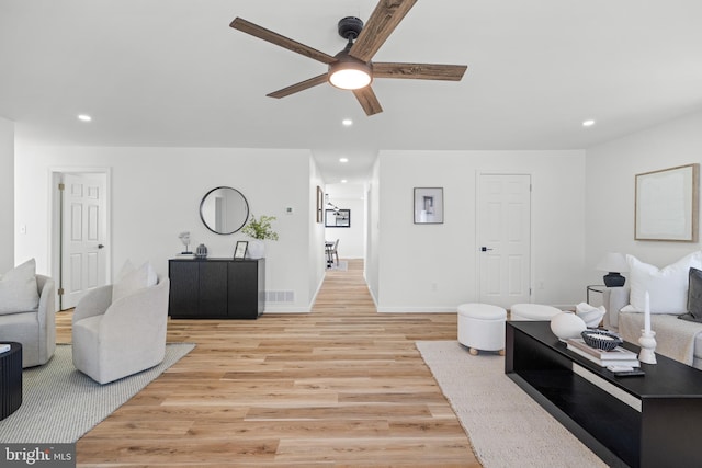 living area featuring baseboards, recessed lighting, a ceiling fan, and light wood-style floors