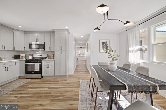 kitchen with light wood finished floors, stainless steel appliances, light countertops, and tasteful backsplash