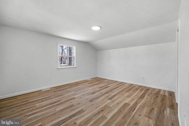 bonus room with vaulted ceiling, baseboards, light wood-type flooring, and visible vents