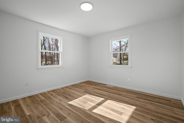 unfurnished room featuring a wealth of natural light, baseboards, and wood finished floors