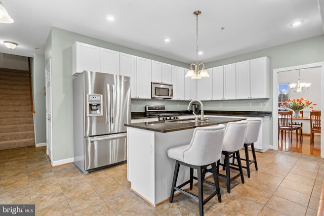 kitchen with a chandelier, appliances with stainless steel finishes, a kitchen island with sink, and a sink