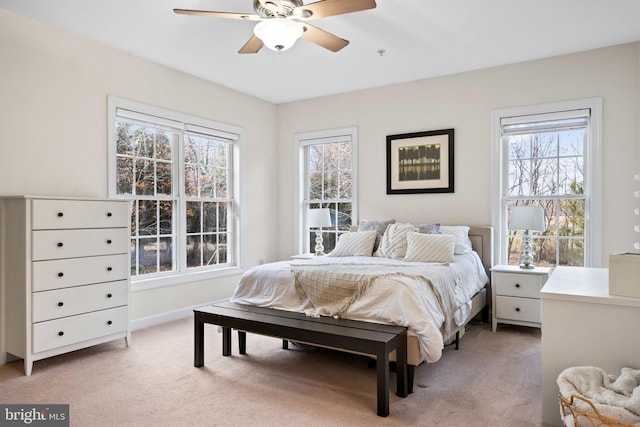 bedroom with a ceiling fan, light colored carpet, and baseboards