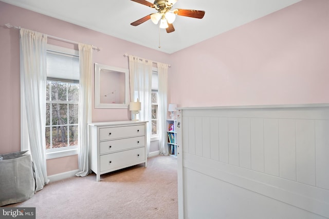 bedroom with ceiling fan, light colored carpet, and wainscoting