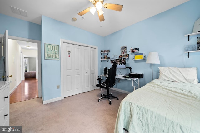 bedroom with visible vents, baseboards, light carpet, a closet, and a ceiling fan