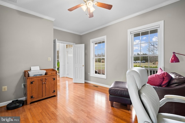 sitting room with light wood finished floors, visible vents, crown molding, baseboards, and a ceiling fan