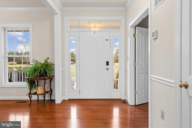 entryway featuring crown molding, wood finished floors, visible vents, and baseboards