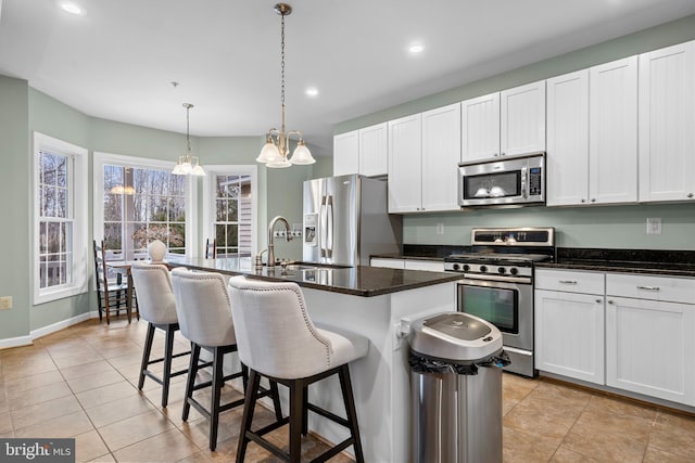 kitchen with a kitchen bar, an island with sink, recessed lighting, appliances with stainless steel finishes, and white cabinets